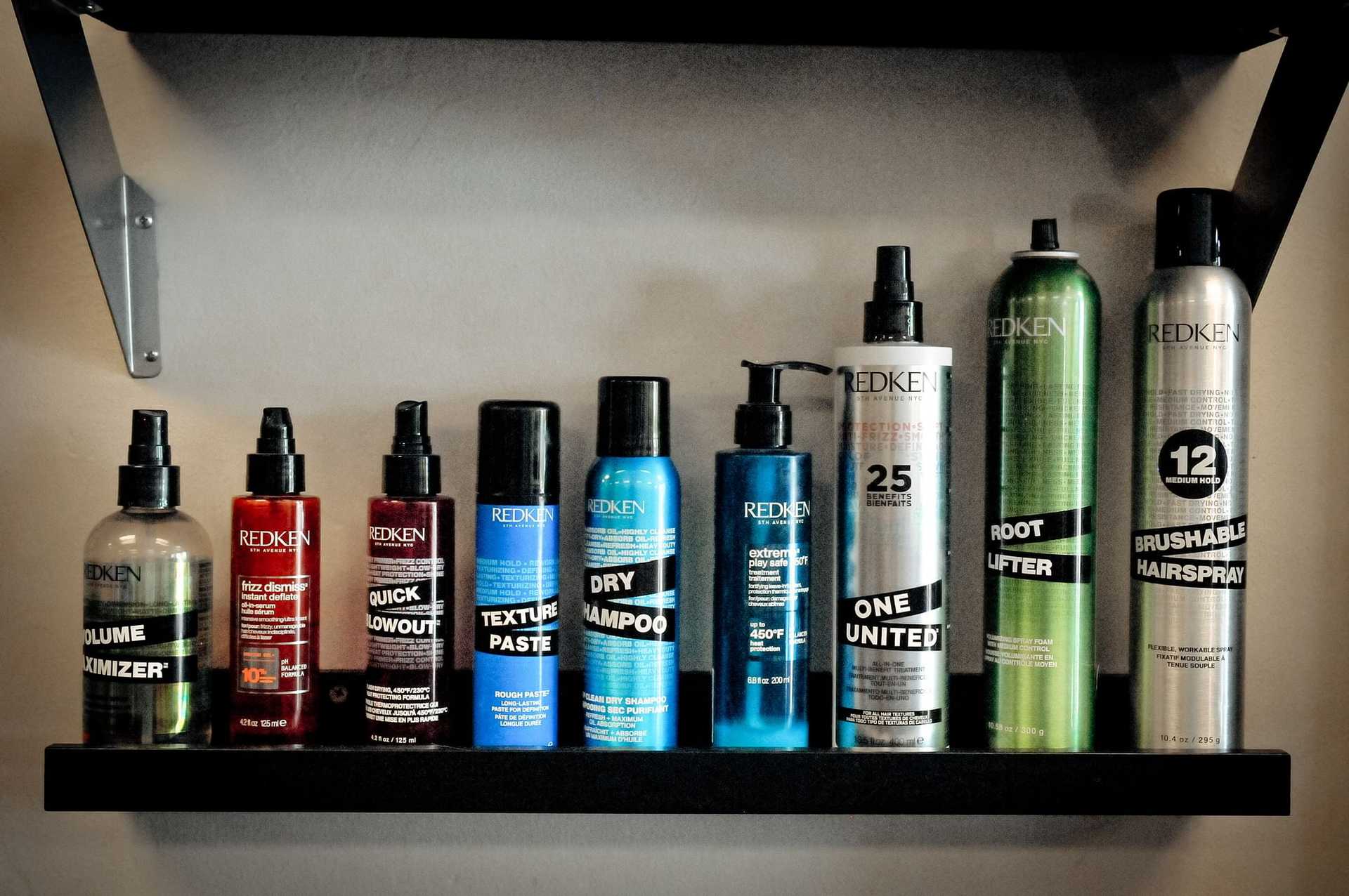 Hair styling products lined up on shelves, including sprays, shampoos, and texturizers.