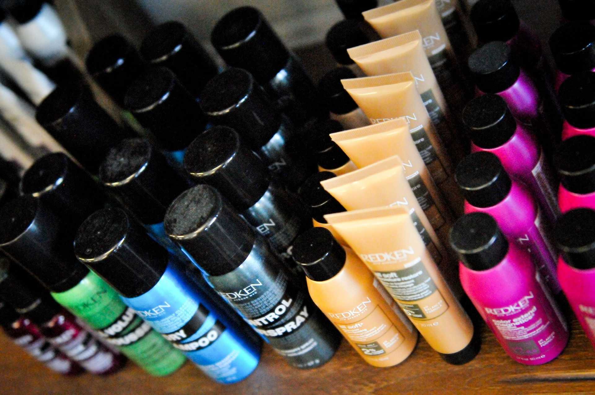 Hair product bottles organized by color and brand on a shelf.