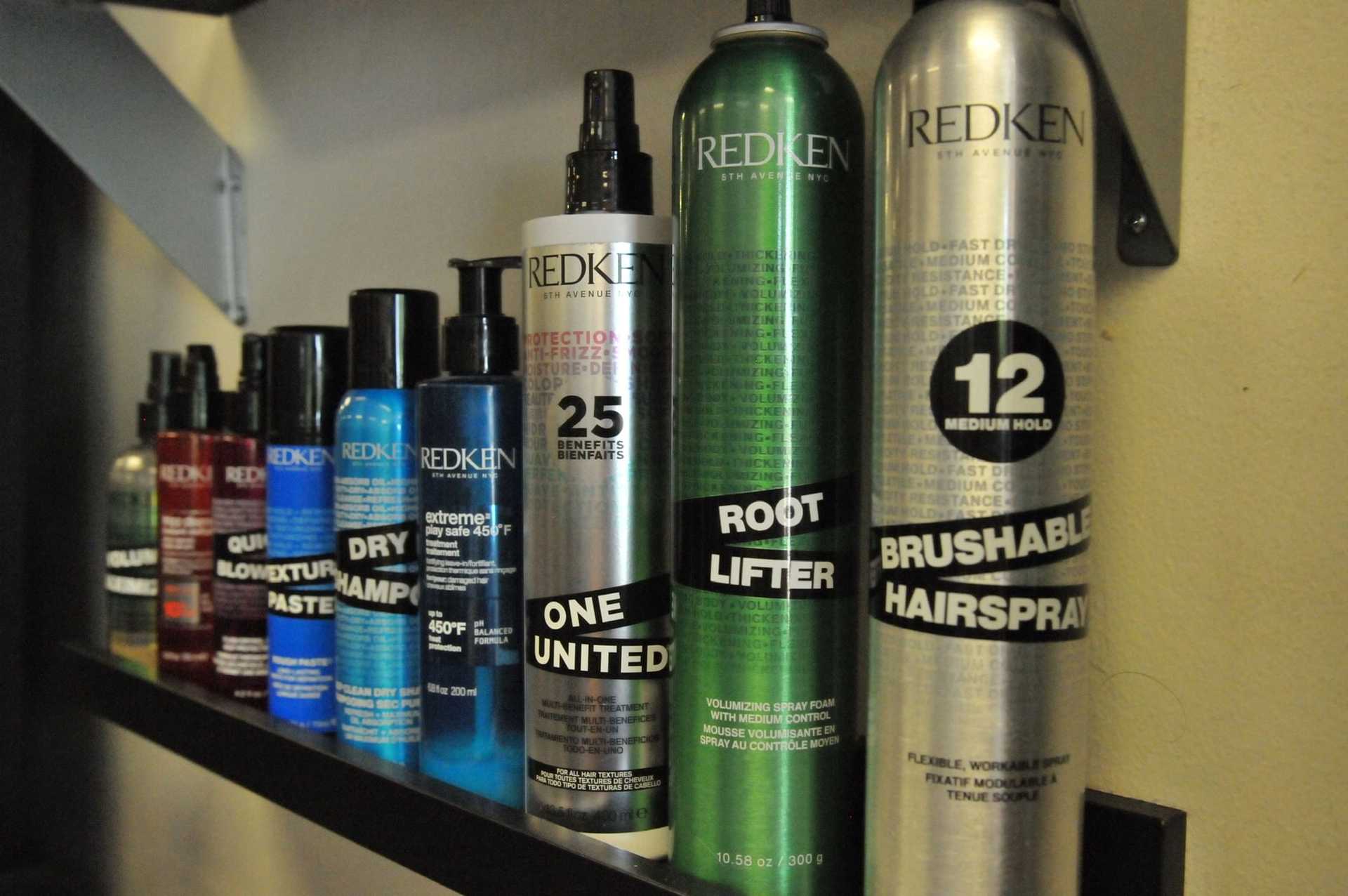 Hair care products lined up on shelf, various Redken styling sprays and bottles.